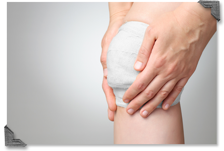 Close up of bandaged knee with hands on the bandage