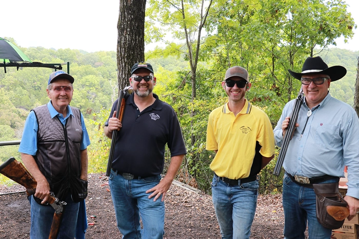 4 men with shotguns stand in the woods
